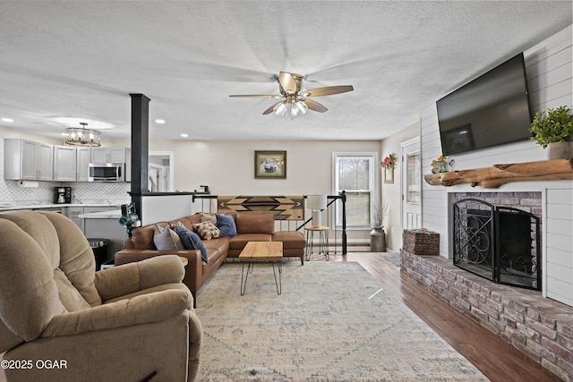 400 Silverwood Ln, Joplin, MO 64801 - living area with wood finished floors, a ceiling fan, a textured ceiling, a fireplace, and a chandelier