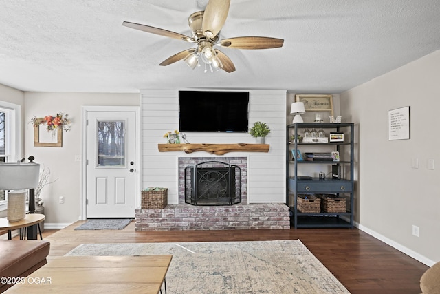 400 Silverwood Ln, Joplin, MO 64801 - living room featuring wood finished floors, a textured ceiling, a ceiling fan, a brick fireplace, and baseboards