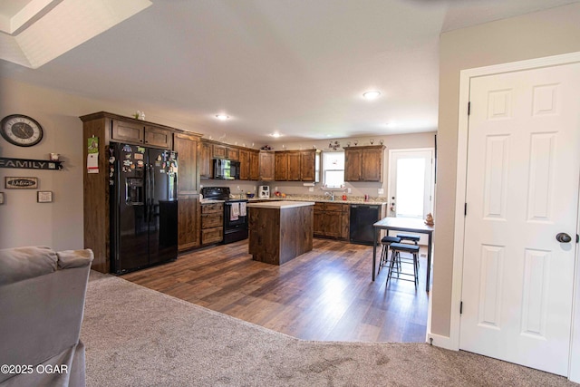 kitchen with a center island, dark colored carpet, open floor plan, black appliances, and light countertops