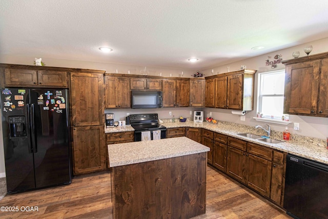 kitchen featuring recessed lighting, a kitchen island, a sink, dark wood-type flooring, and black appliances