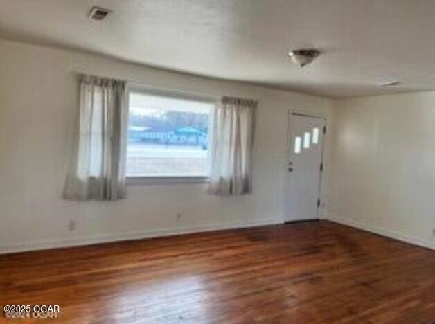 foyer with baseboards, visible vents, and wood finished floors