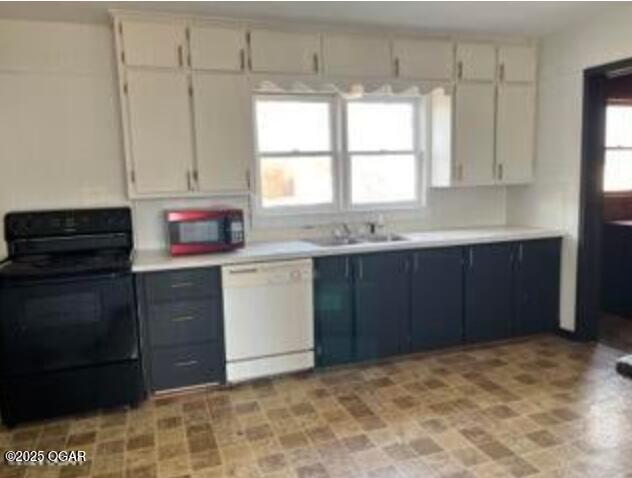 kitchen featuring light countertops, a sink, gray cabinets, black electric range oven, and dishwasher