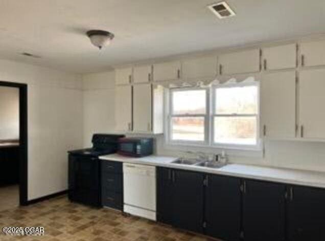 kitchen with white dishwasher, dark cabinets, a sink, black electric range, and light countertops