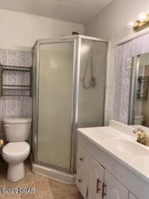 bathroom featuring tile patterned floors, vanity, toilet, and a stall shower