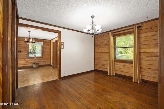 6309 Impala Dr, Joplin, MO 64804 - spare room with a chandelier, wooden walls, crown molding, dark wood-style flooring, and a textured ceiling