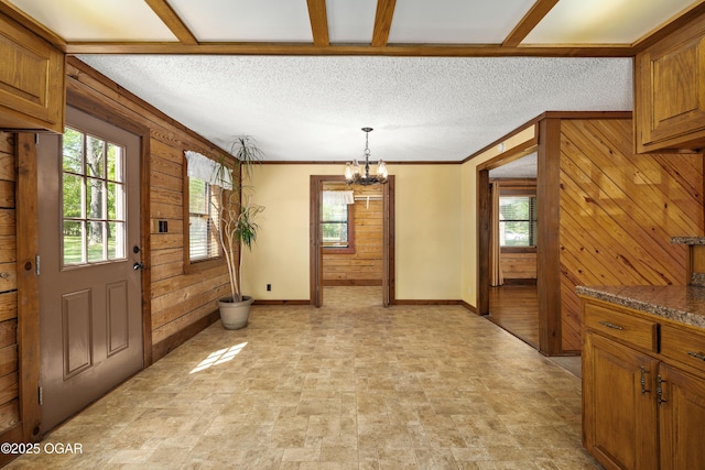 6309 Impala Dr, Joplin, MO 64804 - unfurnished dining area featuring wood walls, baseboards, a chandelier, and a textured ceiling