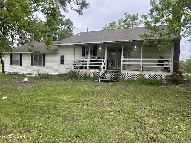 rear view of property with a lawn, covered porch, and a shingled roof