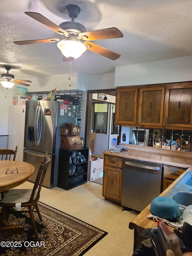 kitchen featuring stainless steel appliances, a ceiling fan, a textured ceiling, light countertops, and light flooring