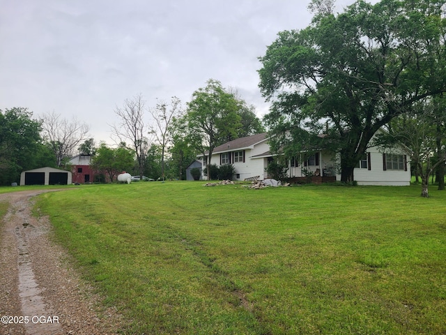 view of grassy yard with a garage, driveway, and an outbuilding
