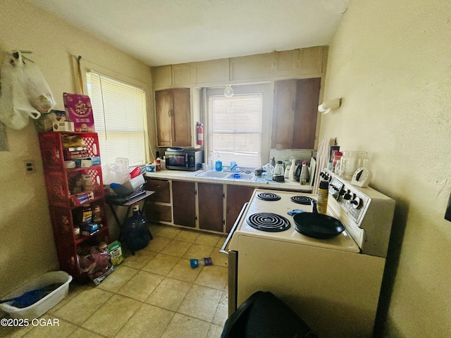 kitchen featuring white electric range, light countertops, light tile patterned floors, and a sink