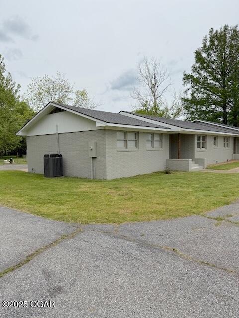 view of home's exterior with central air condition unit and a yard
