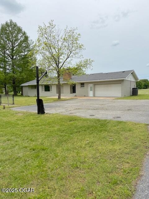 ranch-style home with a front yard, cooling unit, an attached garage, and driveway