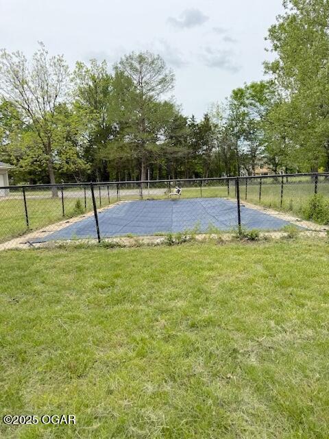 view of basketball court featuring fence and a lawn