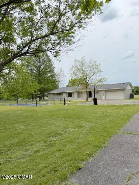 view of front of home with a garage, driveway, fence, and a front yard