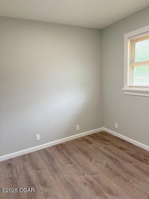 spare room with baseboards and wood finished floors