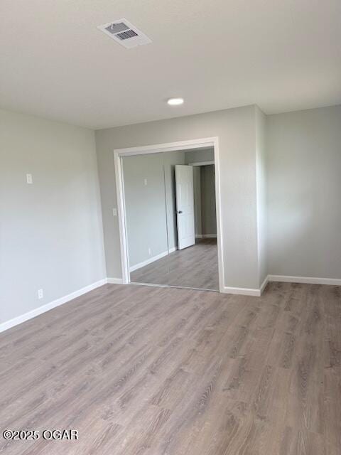 unfurnished room featuring baseboards, visible vents, and wood finished floors