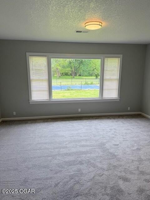 carpeted empty room featuring a textured ceiling and baseboards