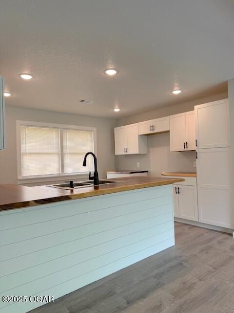 kitchen with white cabinetry, light wood-style floors, recessed lighting, and a sink