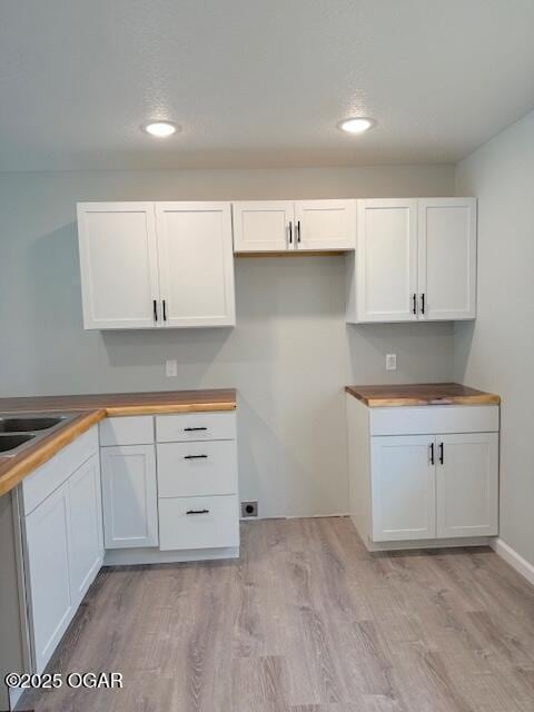 kitchen featuring white cabinets, butcher block countertops, light wood-style flooring, and recessed lighting