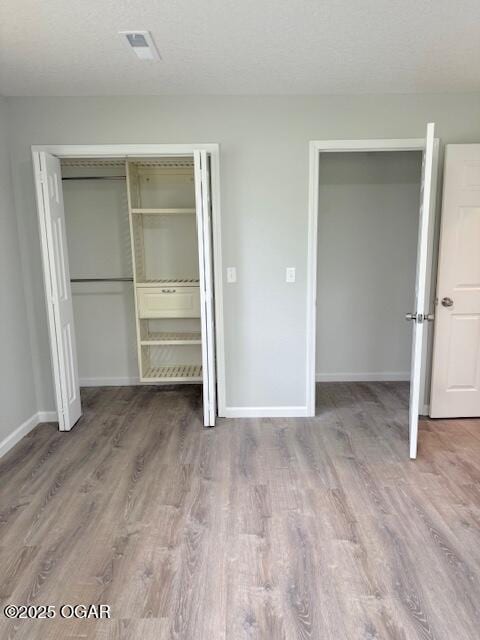 unfurnished bedroom featuring baseboards, visible vents, and wood finished floors