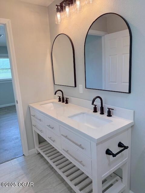 bathroom featuring a sink, double vanity, baseboards, and wood finished floors