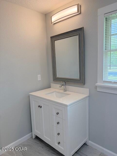 bathroom with baseboards, vanity, and a textured ceiling