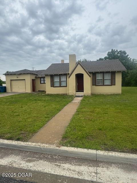 407 Porter, Joplin, MO 64801 - single story home with stucco siding, an attached garage, a front lawn, and driveway