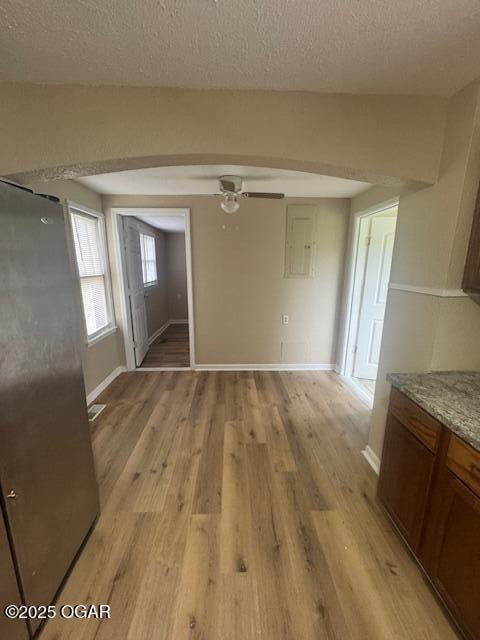 407 Porter, Joplin, MO 64801 - unfurnished dining area featuring arched walkways, light wood-style floors, a ceiling fan, baseboards, and a textured ceiling