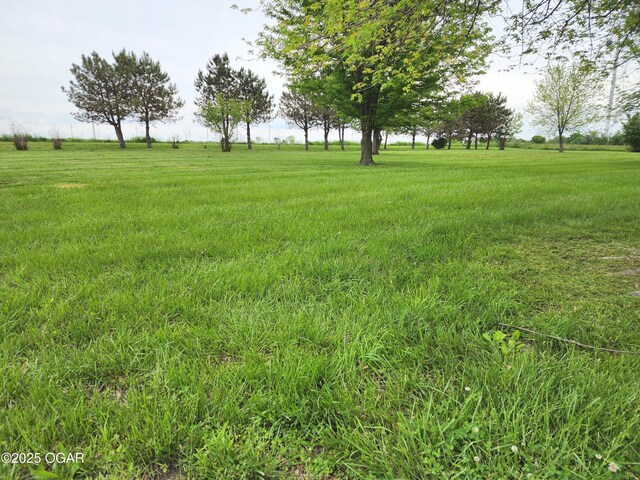 view of green lawn with a rural view