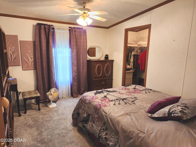 carpeted bedroom with a textured ceiling, ornamental molding, a spacious closet, a closet, and a ceiling fan