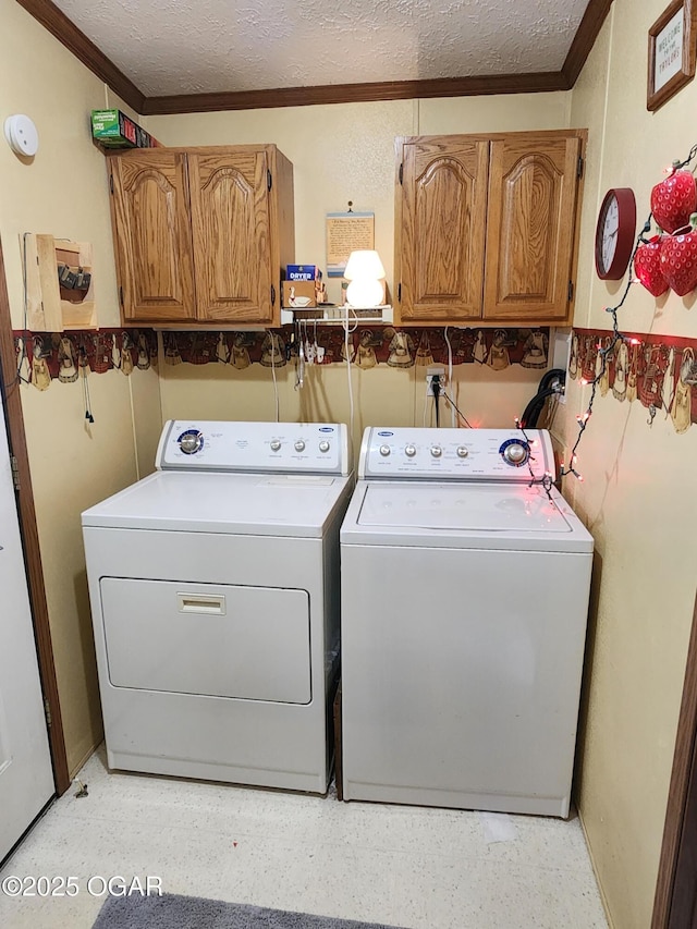 laundry room featuring cabinet space, washing machine and dryer, ornamental molding, and a textured ceiling