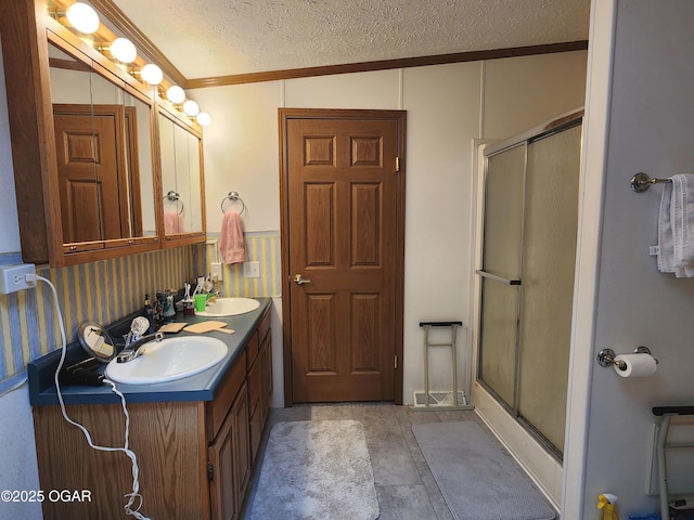 full bath featuring crown molding, a stall shower, double vanity, and a textured ceiling