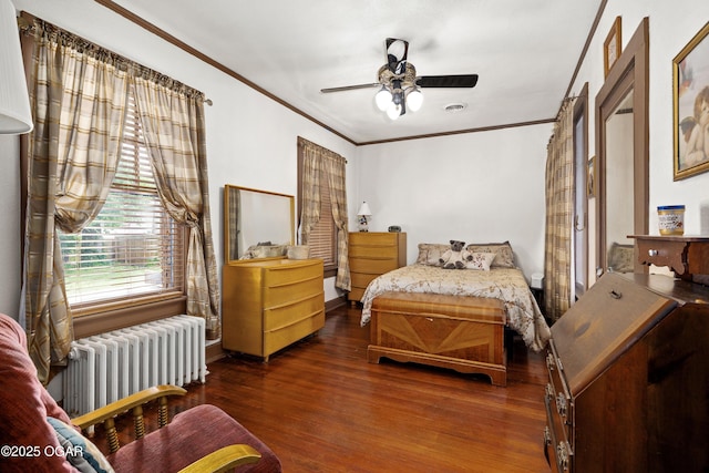 bedroom with radiator, wood finished floors, ornamental molding, and a ceiling fan