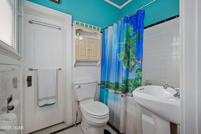 bathroom with tile walls, tile patterned flooring, toilet, a sink, and a shower with curtain