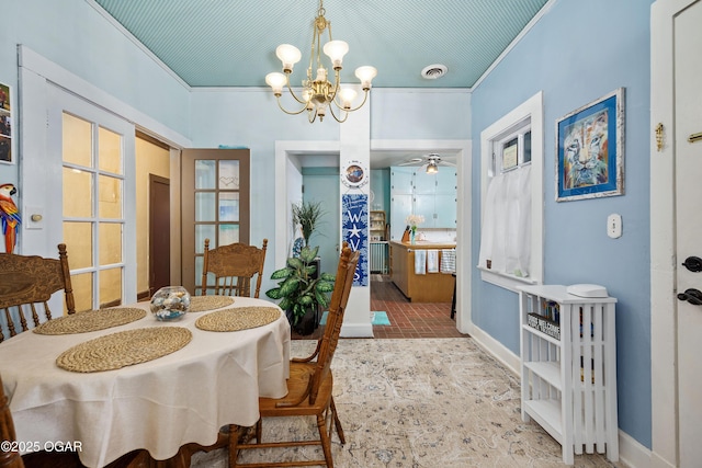 dining space featuring a chandelier, crown molding, baseboards, and ceiling fan
