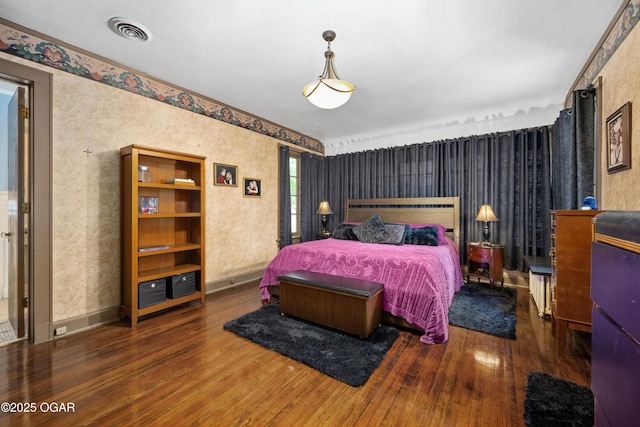 bedroom with wood finished floors, wallpapered walls, and baseboards