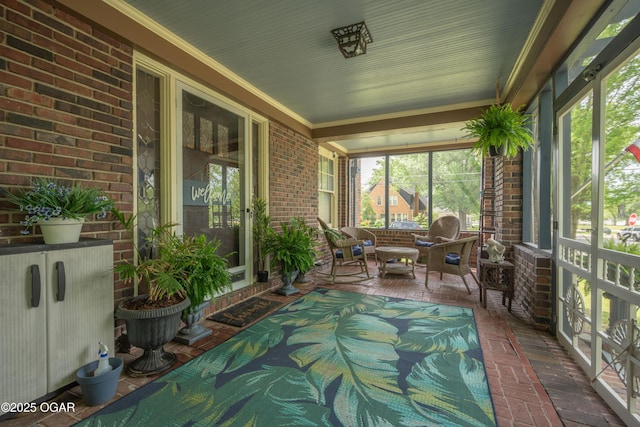 sunroom featuring brick floors, brick wall, and crown molding