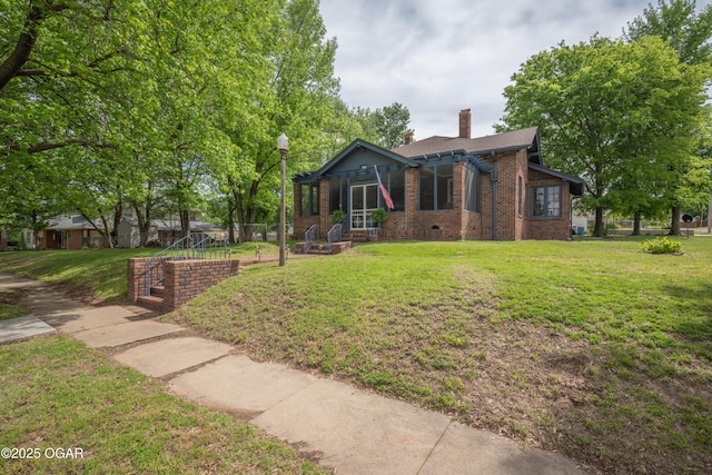 view of front of home featuring brick siding, a chimney, and a front yard