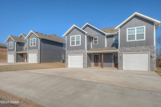 view of front of home with stone siding, an attached garage, concrete driveway, and central AC