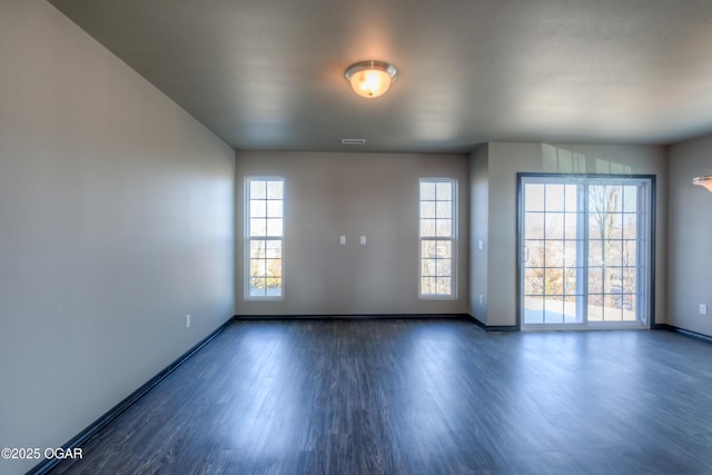 spare room featuring baseboards and dark wood-style floors