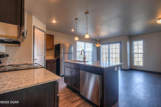 kitchen featuring stainless steel appliances, a sink, dark wood finished floors, an island with sink, and hanging light fixtures