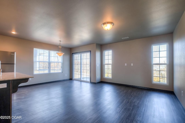 unfurnished dining area with dark wood-style flooring and baseboards
