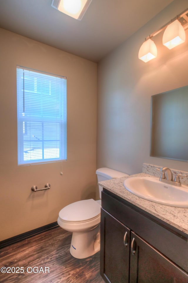 half bathroom featuring wood finished floors, toilet, and vanity