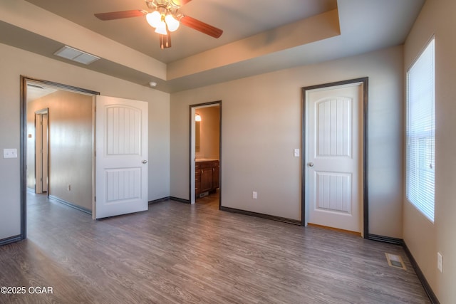 unfurnished bedroom featuring multiple windows, wood finished floors, and baseboards