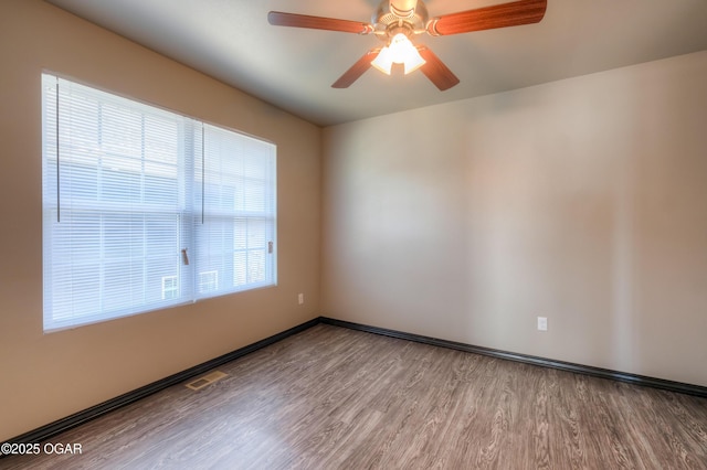 empty room with wood finished floors, ceiling fan, and baseboards