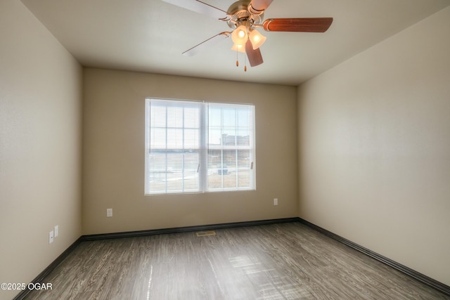 empty room with wood finished floors, a ceiling fan, and baseboards
