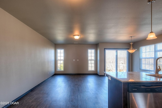 kitchen featuring stainless steel dishwasher, baseboards, wood finished floors, a sink, and hanging light fixtures