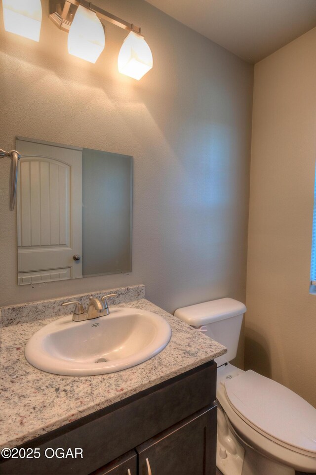 half bathroom with vanity and toilet
