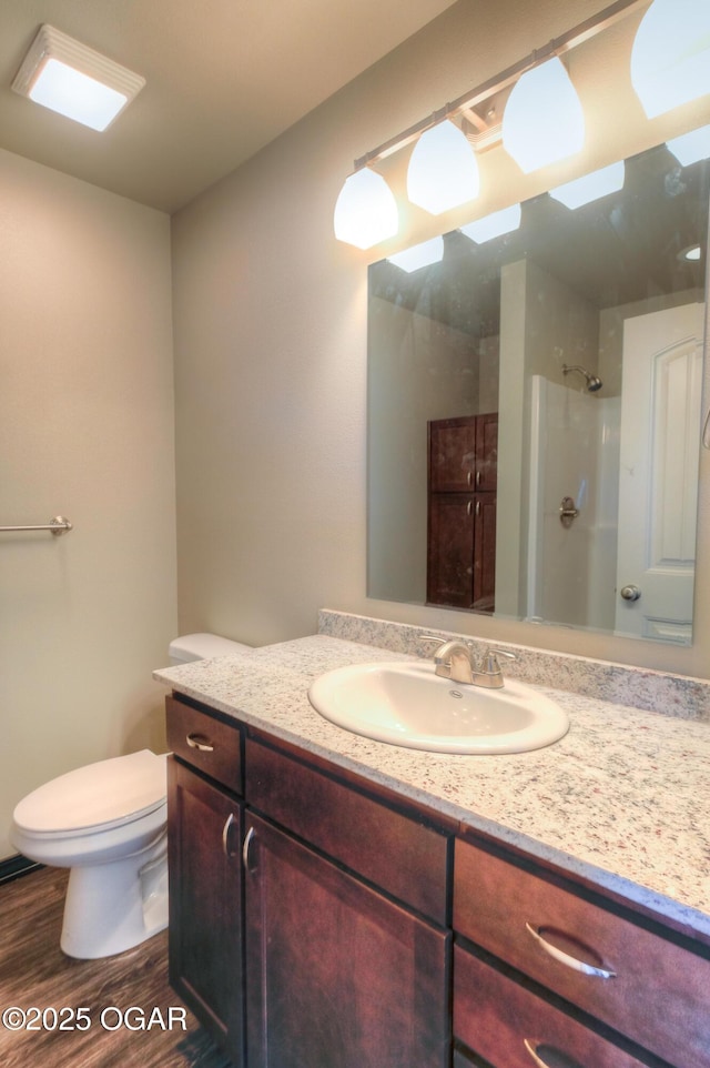 bathroom featuring wood finished floors, a shower, vanity, and toilet