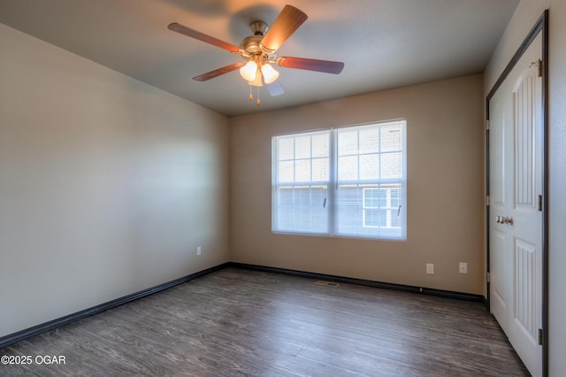 empty room with wood finished floors, ceiling fan, and baseboards